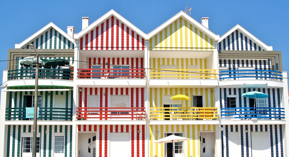 Casas com listras coloridas, enfileiradas na Praia de Aveiro.