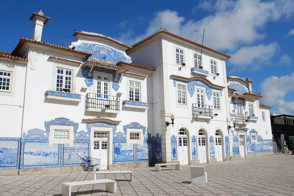 Fachada da Estação de Aveiro, com paredes brancas e cheias de azulejos.