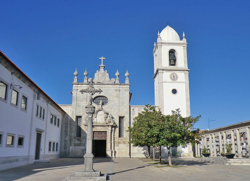 Pátio em frente à Sé Catedral de Aveiro, com uma cruz e algumas árvores.