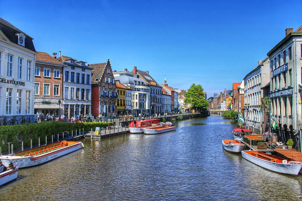 Canal em Ghent, na Bélgica, com vários barcos e casas tradicionais nas laterais.