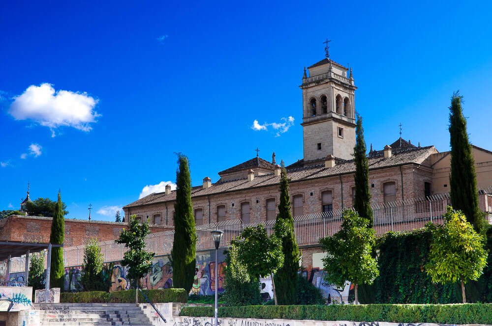 Mosteiro de São Jerônimo, com paredes de tijolos claros e um jardim com árvores.