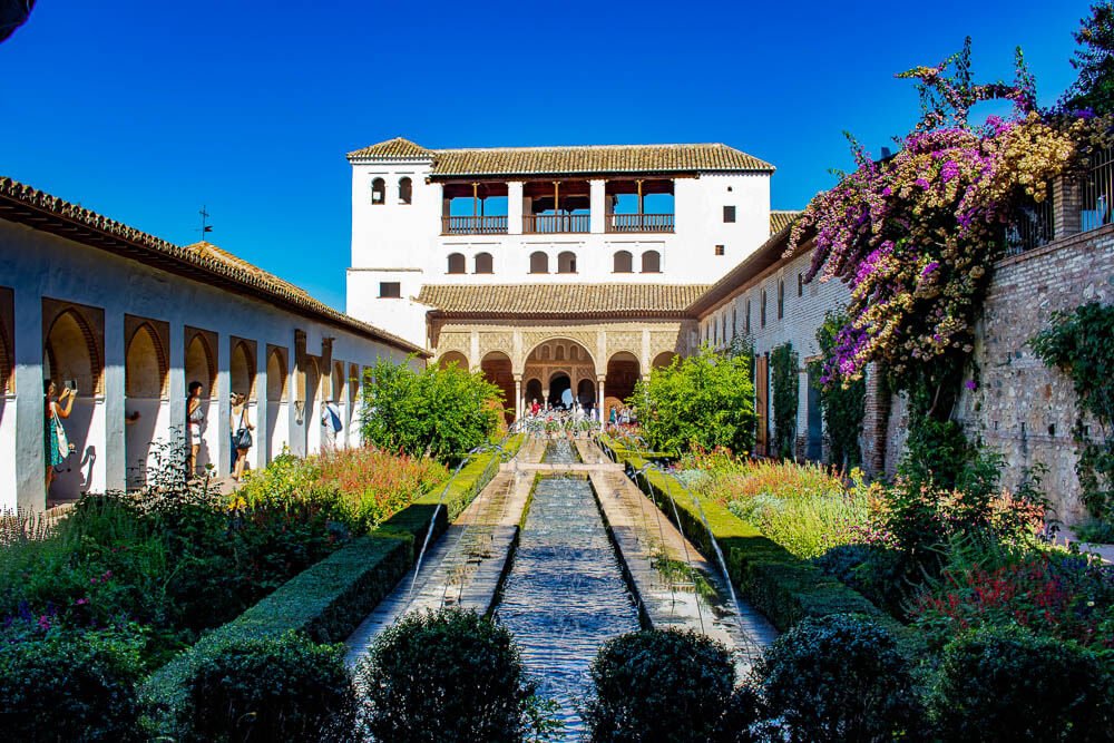 Jardim e fonte do Palácio Generalife, com muitas plantas, e uma fonte no centro.