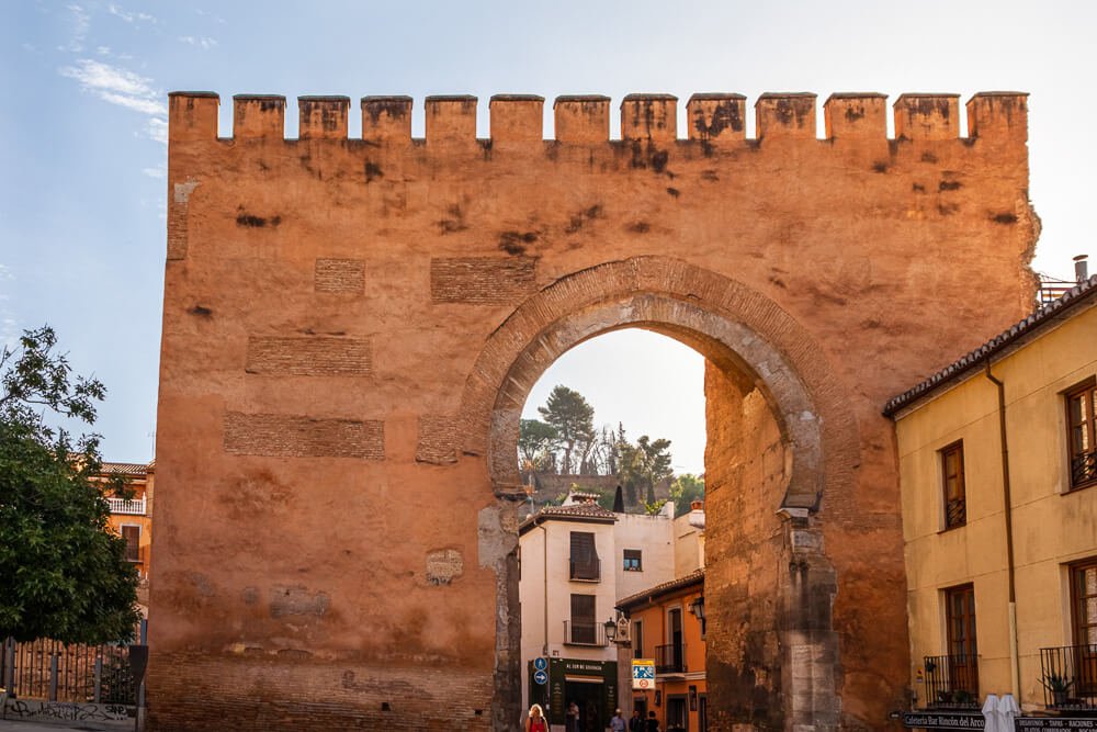 Puerta de Elvira, com paredes claras, um arco e prédios ao lado.