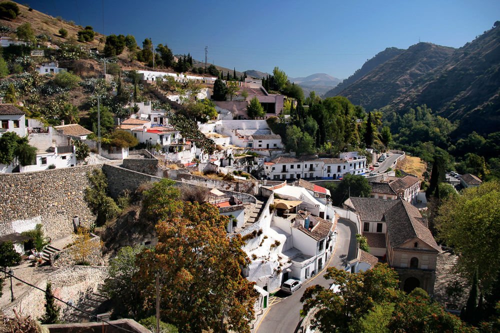 Panorama de Sacromonte, com várias árvores, casas brancas e montanhas.