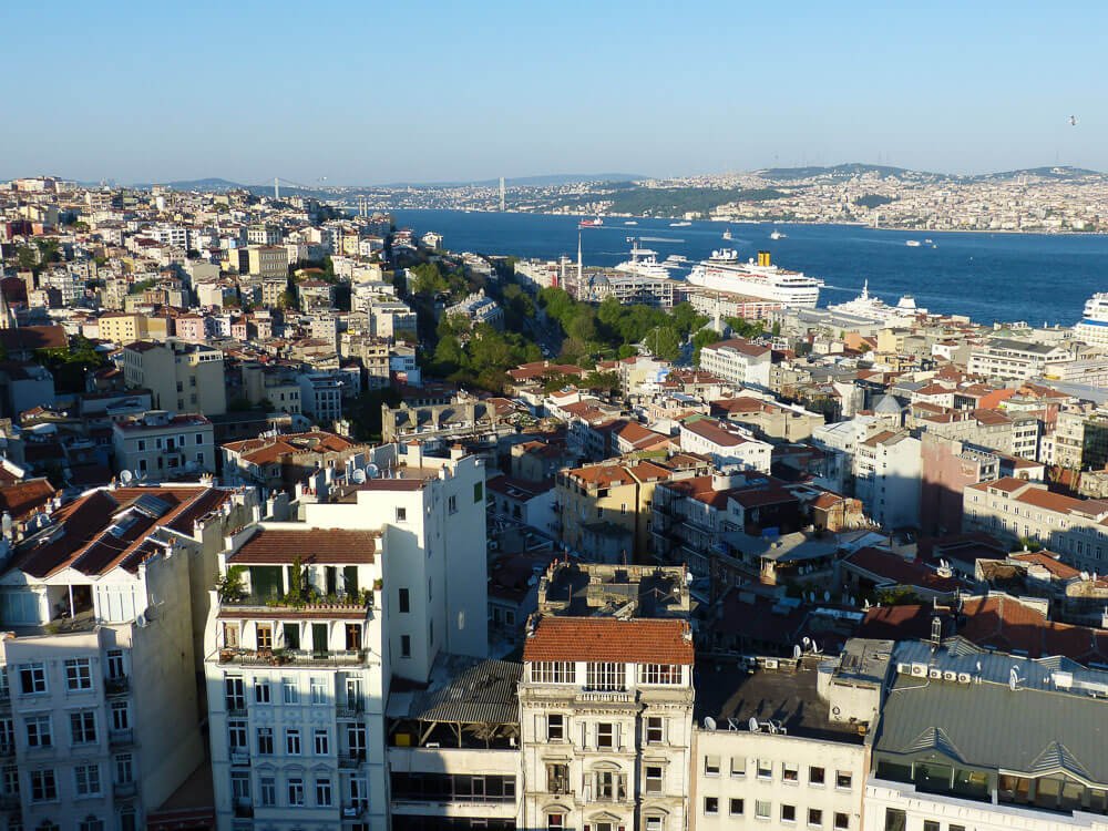 Istambul vista de cima, com vários prédios, árvores e o Estreito de Bósforo.