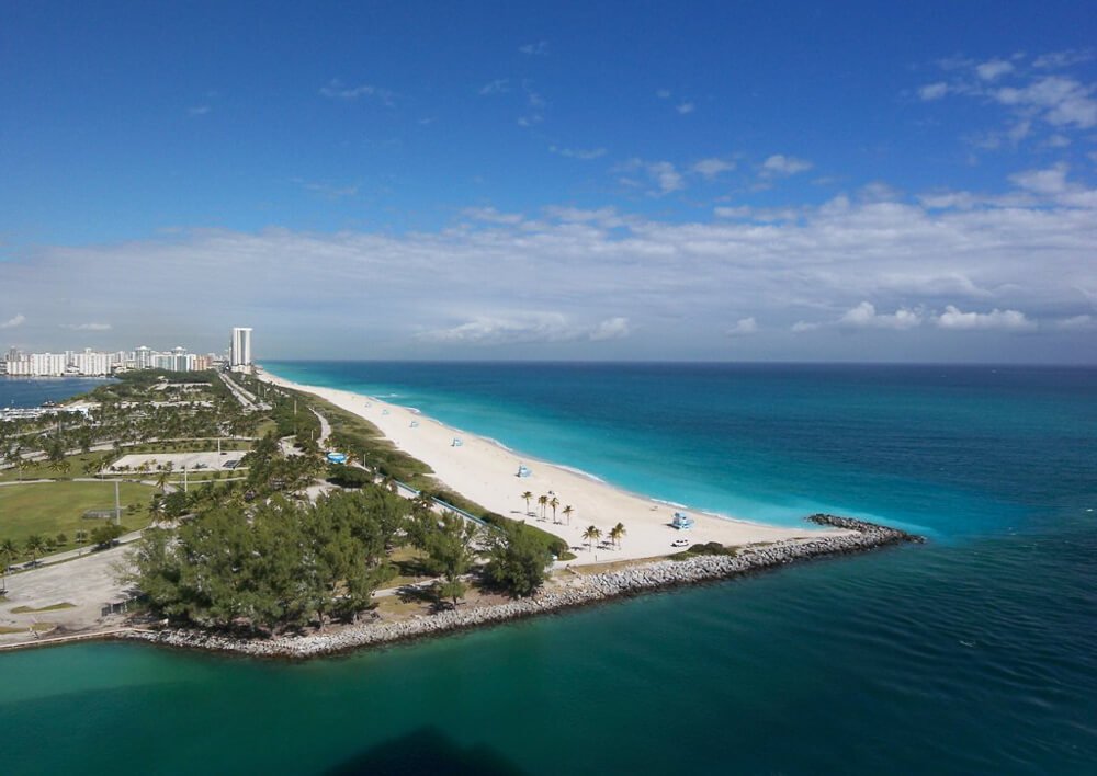 Região de Bal Harbour vista de cima, com várias árvores, areia clara e mar azul-turquesa.