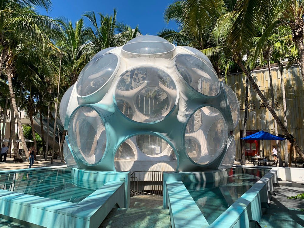 Buckminster Fuller's Fly's Eye Dome, com piscinas nas laterais e coqueiros nos arredores.