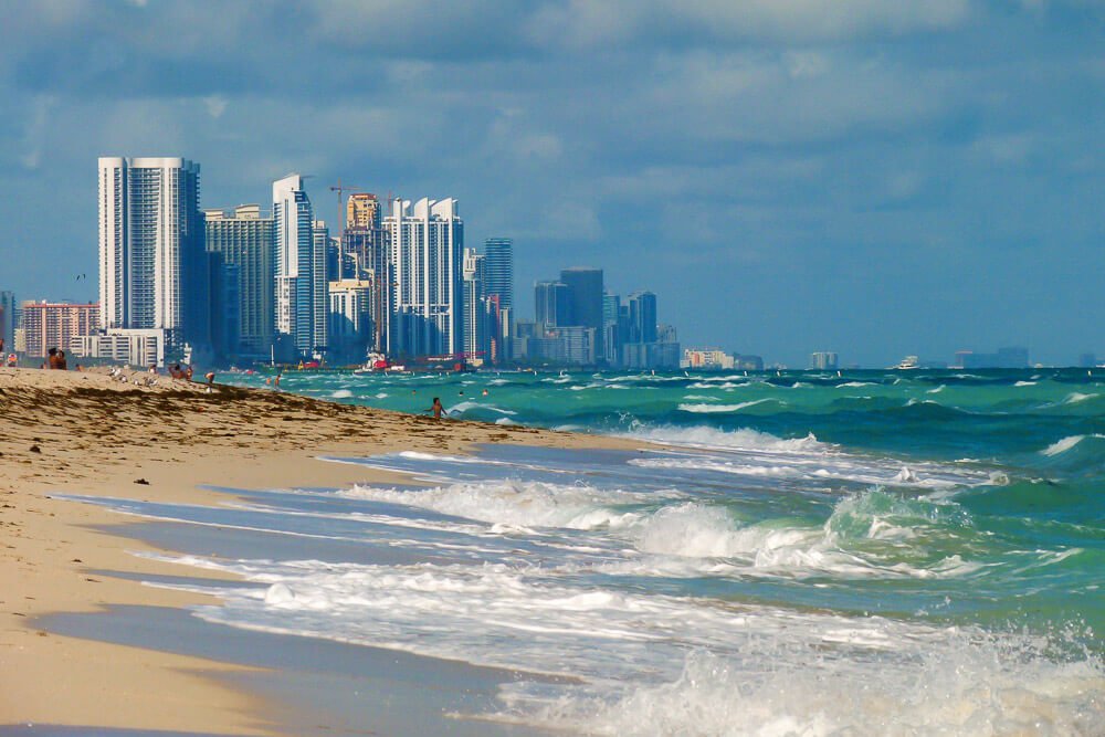 North Beach, com mar agitado, faixa de areia estreita e prédios distantes.