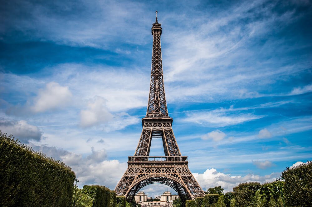 Vista para a Torre Eiffel rodeada por árvores podadas.