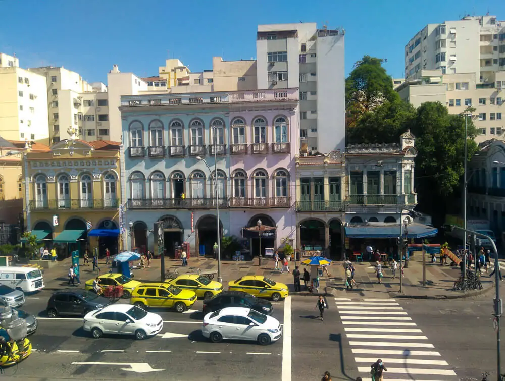 Rua do Catete, com prédios coloridos e antigos, muitos pedestres e automóveis.