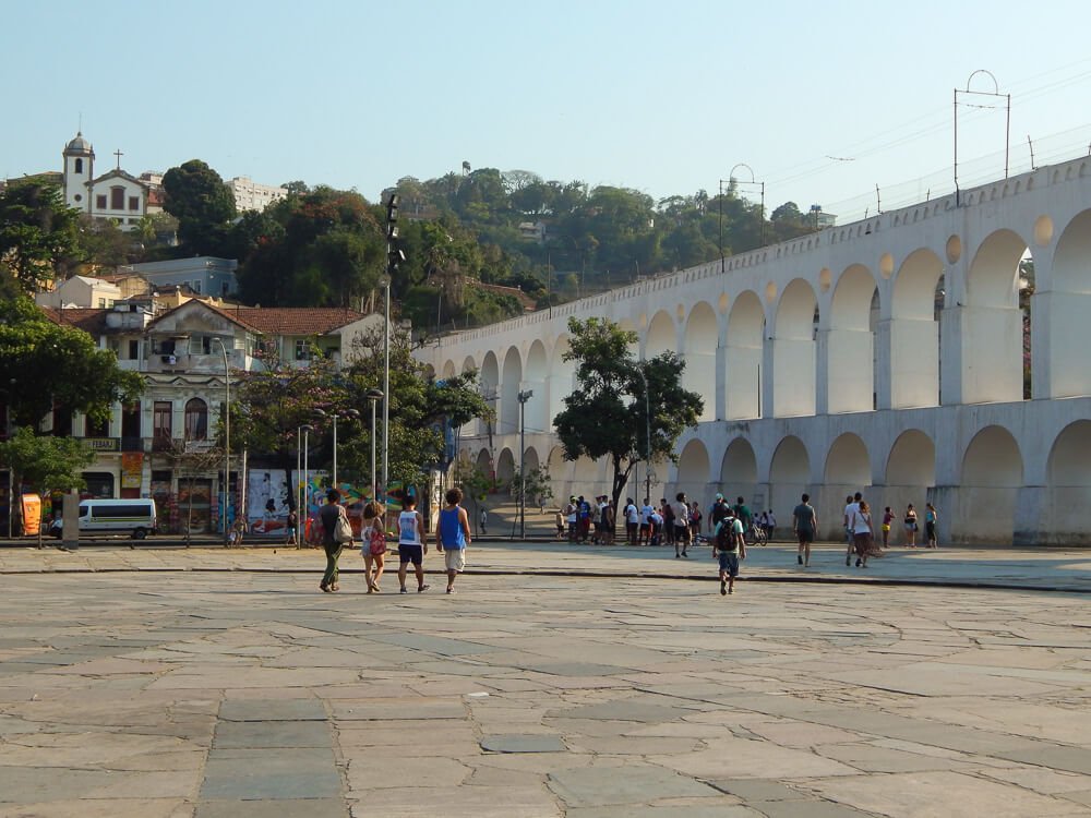 Arcos da lapa com pátio em frente e várias árvores na lateral esquerda.