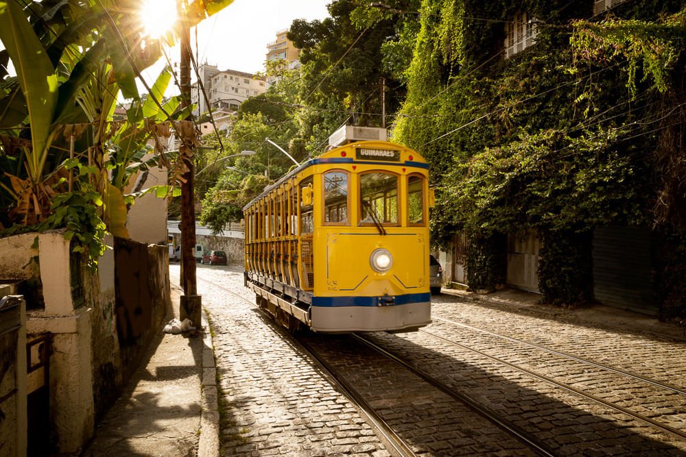 Bonde de Santa Teresa em uma rua estreita e com várias plantas.