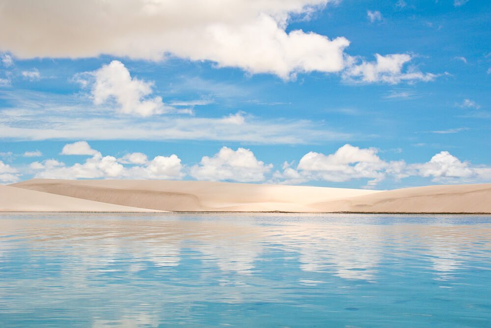 Lagoa dos Lençóis Maranhenses com águas cristalinas refletindo as cores do céu.