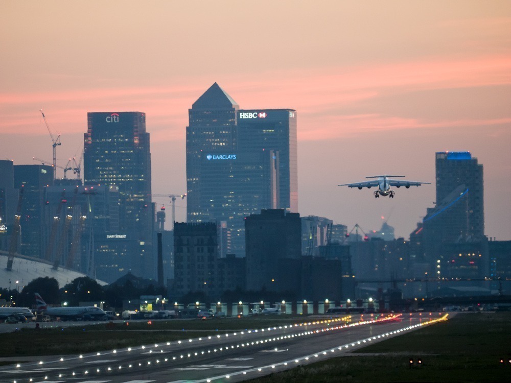 Avião decolando no Aeroporto London City no pôr do sol.