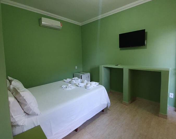 Quarto da Pousada Brisa da Serra com cama de solteiro, ar-condicionado, frigobar e TV.