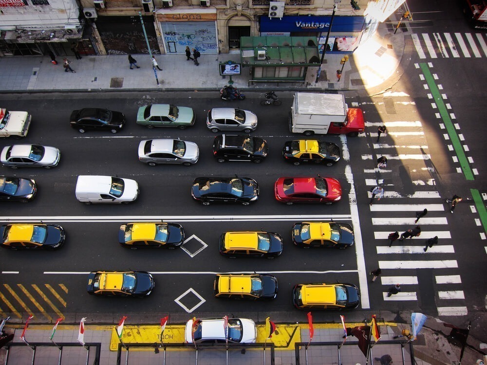 Vista de cima da Avenida Callao, no centro de Buenos Aires durante o dia, com carros parados no sinal e pedestres atravessando na faixa.