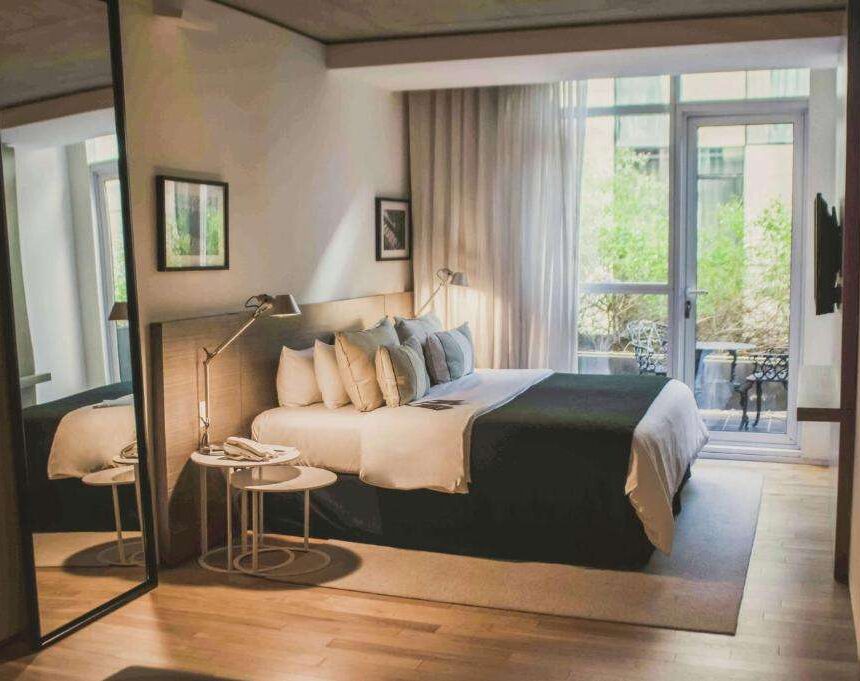 Quarto do hotel Anselmo Buenos Aires, Curio Collection by Hilton, com cama de casal, espelho de corpo inteiro, TV e varanda.