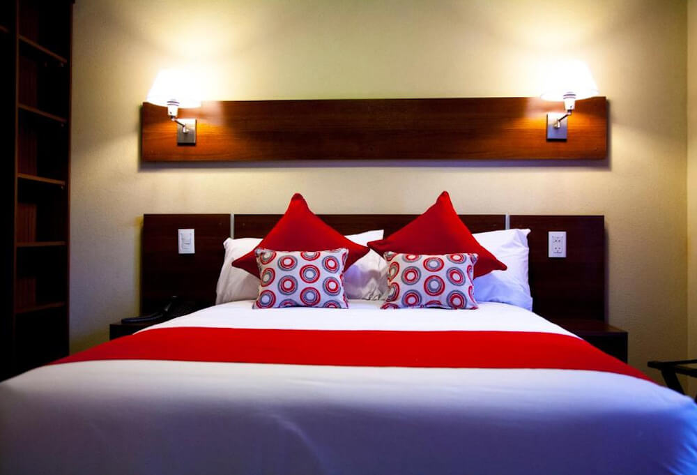 Quarto do hotel First Palermo Hotel, com cama de casal e iluminação aconchegante.