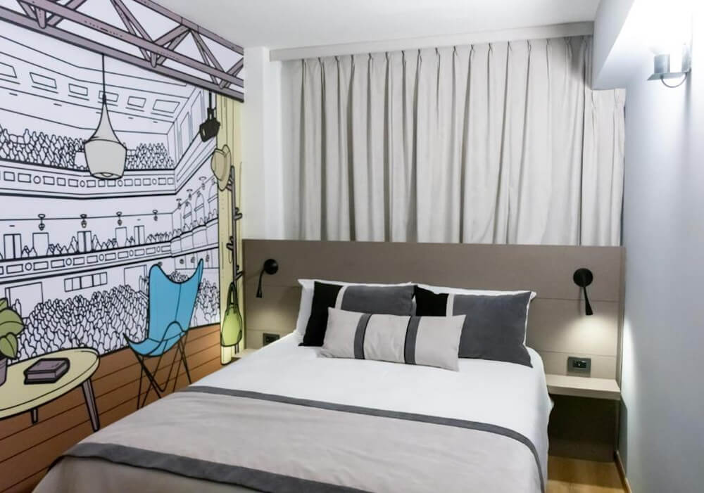 Quarto do hotel ibis Styles Buenos Aires Florida, com cama de casal, janela e parede com painel ilustração.