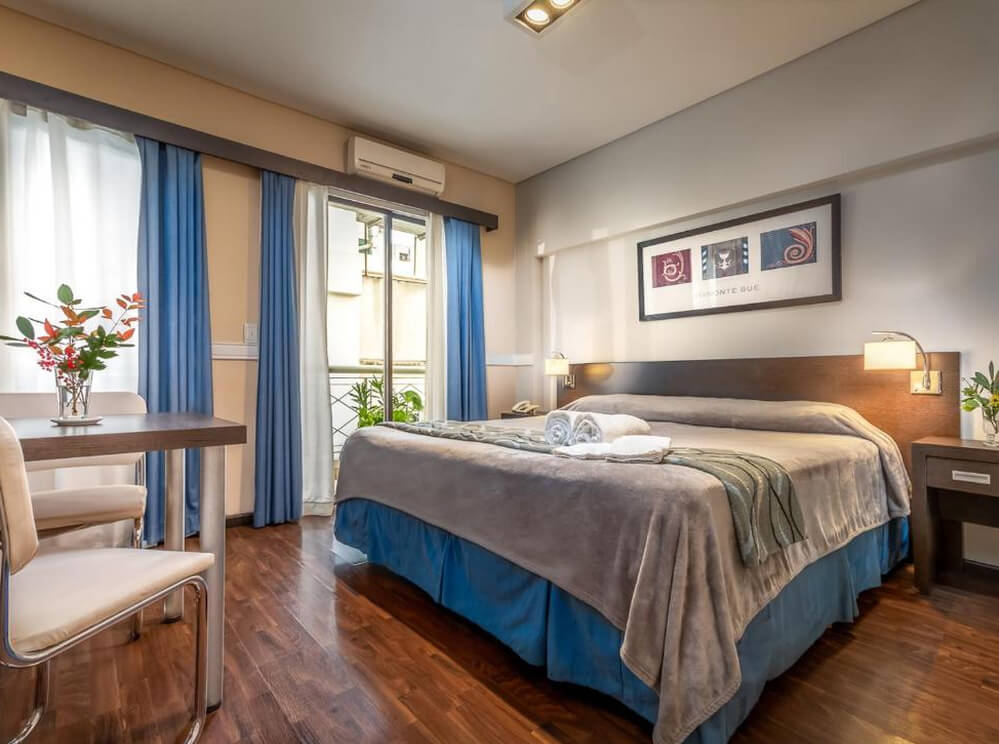 Quarto do hotel Up Viamonte Hotel, com cama de casal, aparelho de ar-condicionado, vasos de plantas e sacada.