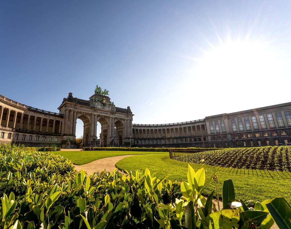 O Arco do Cinquentenário e o jardim do Parque do Cinquentenário, em Bruxelas, durante um dia de sol.