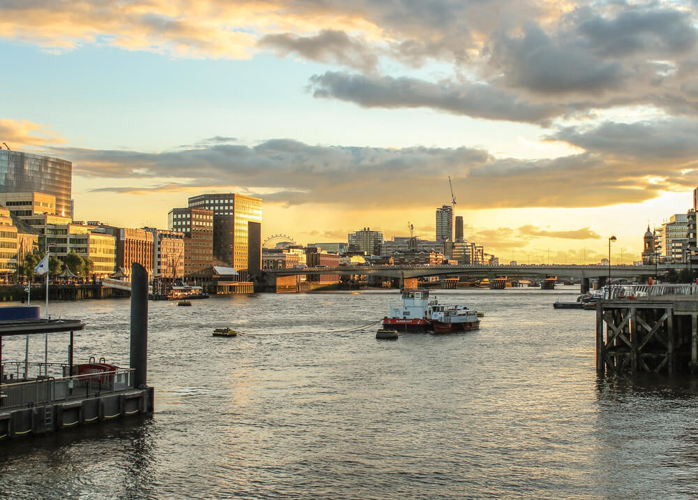 Visão do Rio Tâmisa em Londres, durante o dia, com alguns barcos navegando.