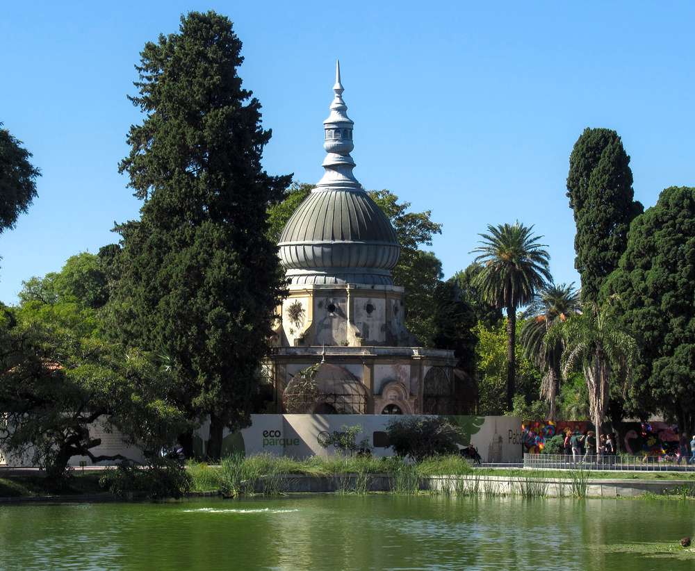 O Pavilhão dos Papagaios, no Ecoparque de Buenos Aires, cercado por árvores e um lago.