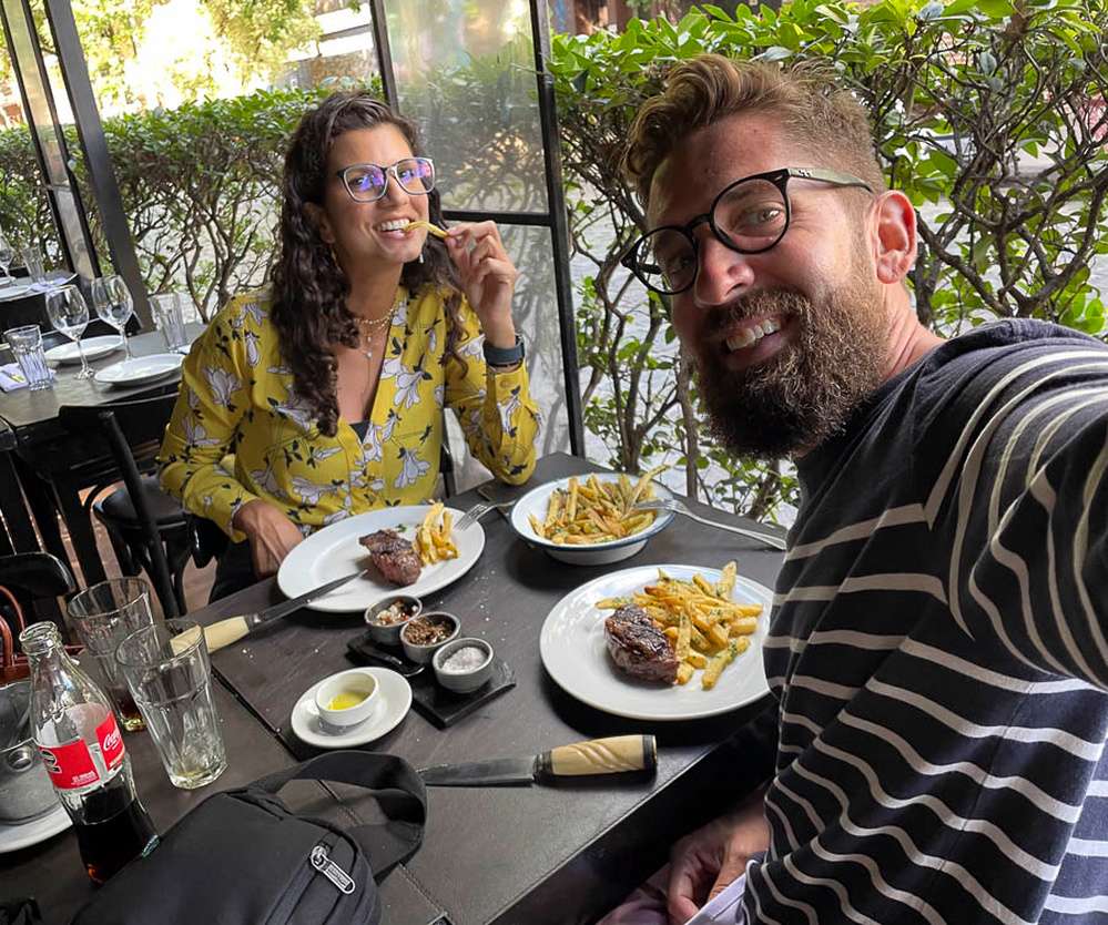 Minha visita ao restaurante Lo de Jesús, no bairro Palermo. Na mesa, há uma garrafa de refrigerante, pratos com comida, e potinhos com molhos.