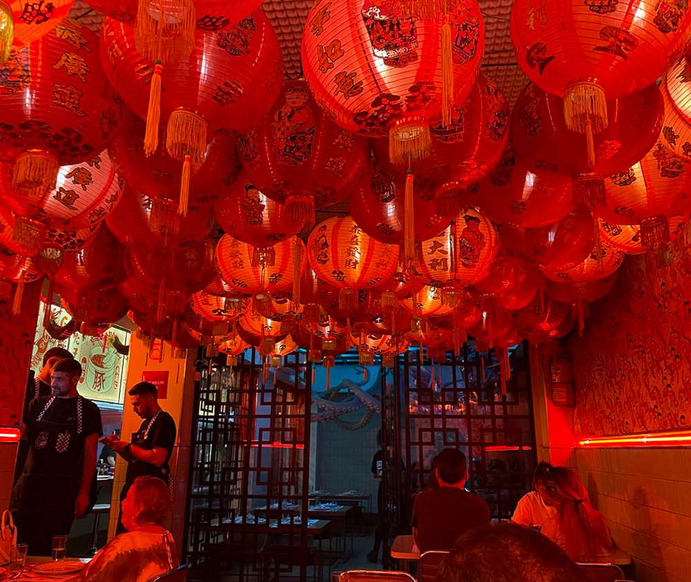 O interior do restaurante Niño Gordo, com iluminação vermelha e teto cheio de lanternas chinesas.