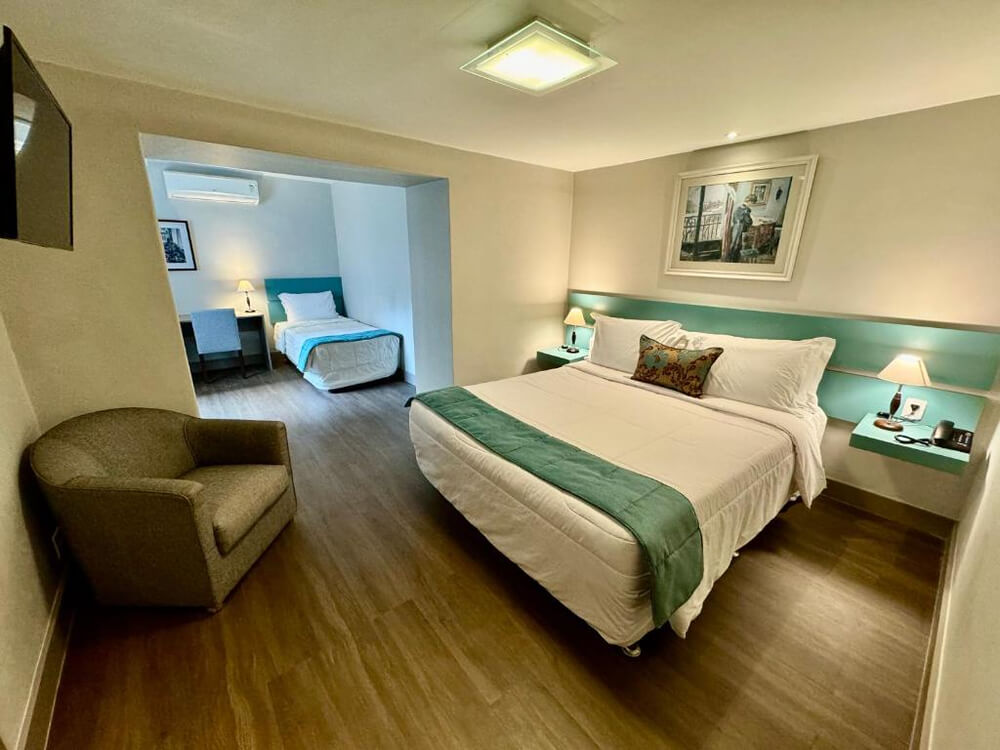 Quarto do Hotel Casablanca Imperial, com uma cama de casal e uma cama de solteiro e chão de madeira.