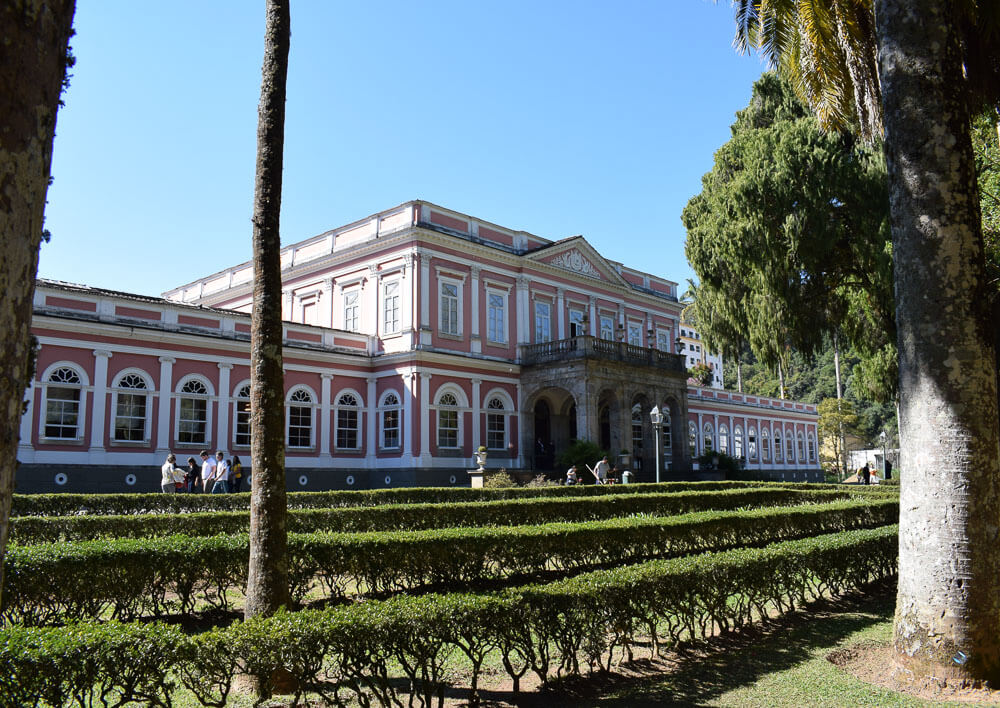 Visão da fachada e de parte do jardim do Museu Imperial, em Petrópolis, durante o dia.