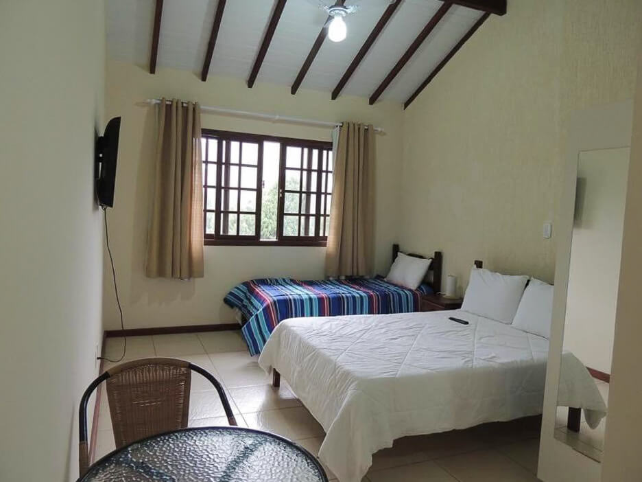 Quarto da Pousada Itaipava Cama e Café, com uma cama de casal e uma cama de solteiro.