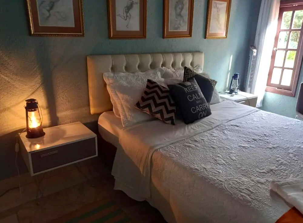 Quarto da Pousada Águas da Serra com cama de casal e lamparina.