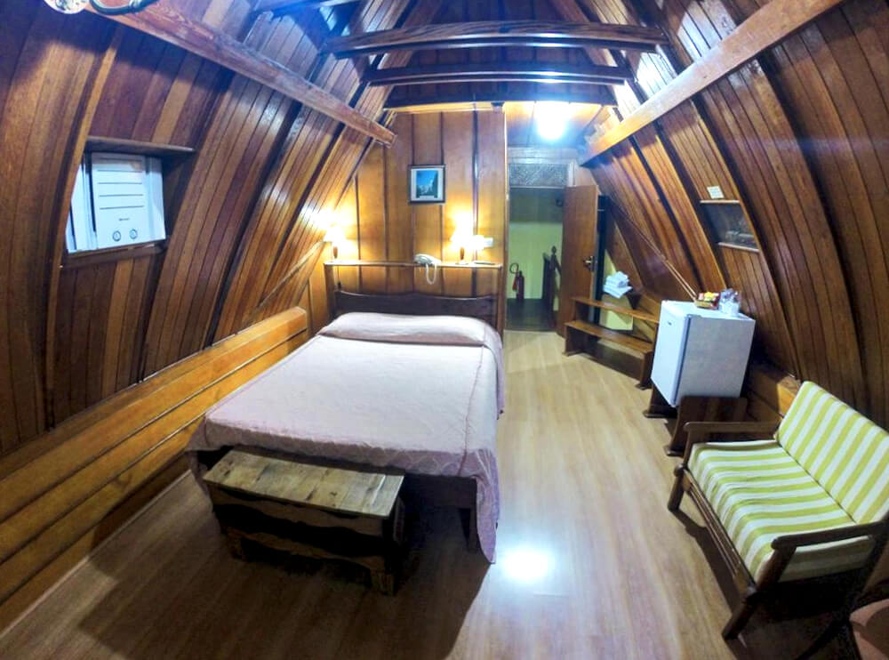 Quarto da Pousada Imperial Koeler, com cama de casal e teto de madeira.