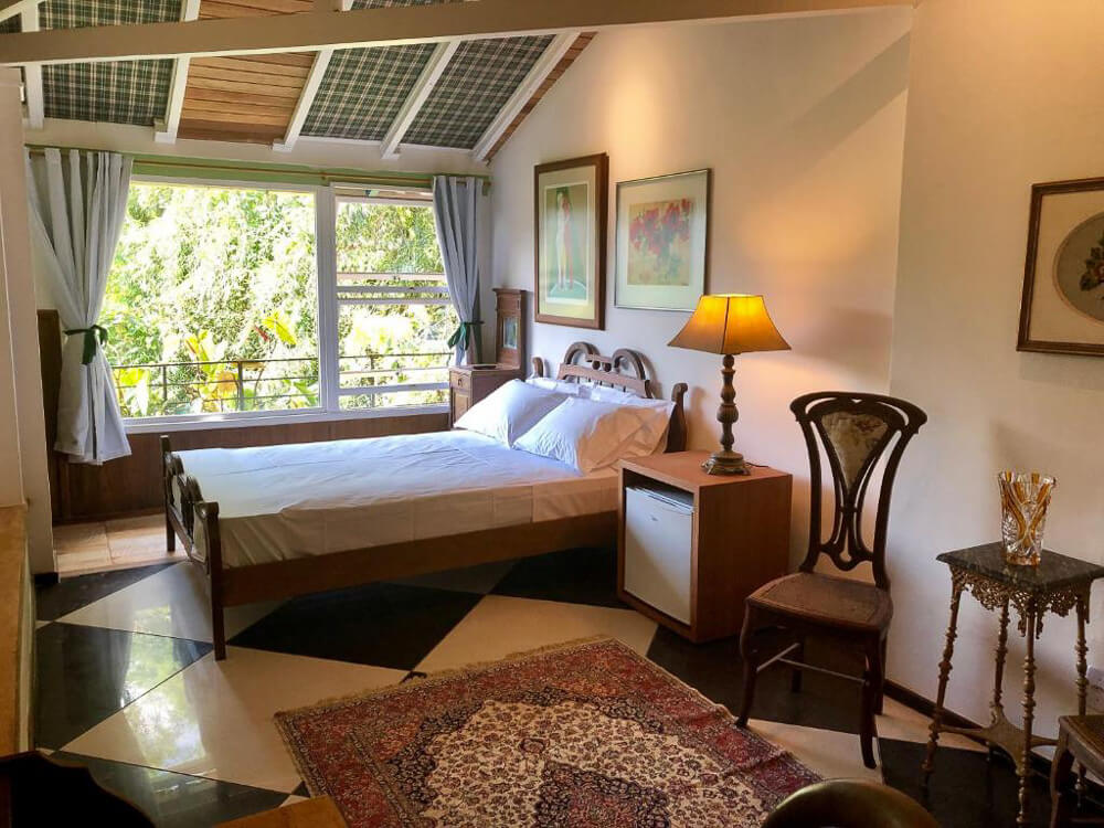 Quarto da Pousada Pataca de Prata, com cama de casal e móveis de madeira.