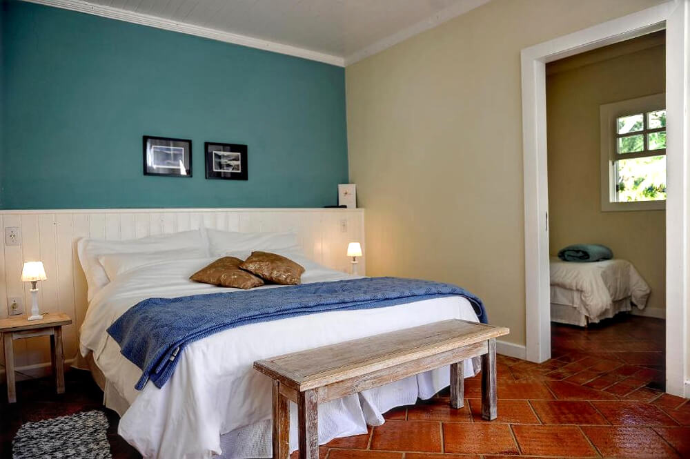 Quarto da Pousada Recanto das Araras, com cama de casal e parede verde.