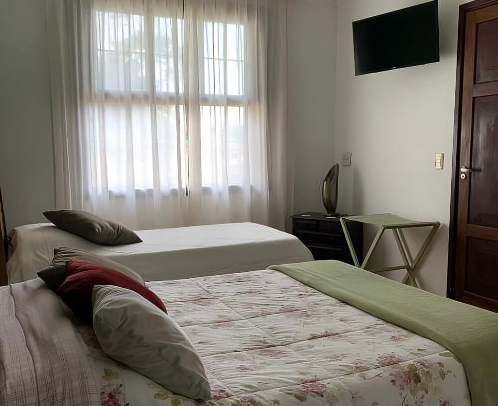 Quarto da Pousada Valparaíso, com uma cama de casal e uma cama de solteiro.