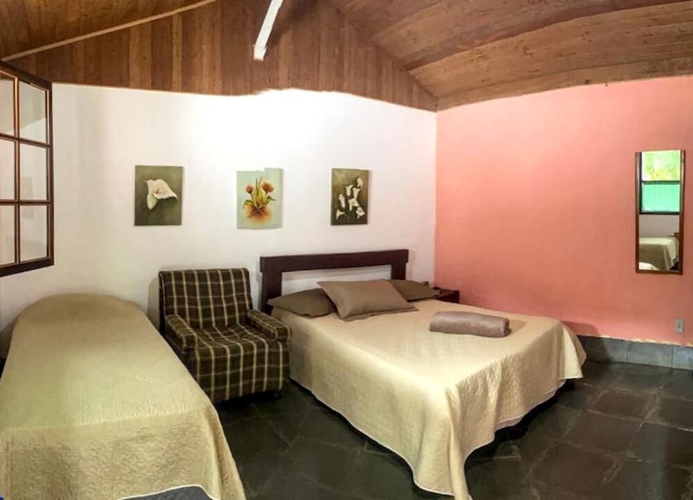 Quarto da pousada Sítio Vivendas, com duas camas e parede rosa.