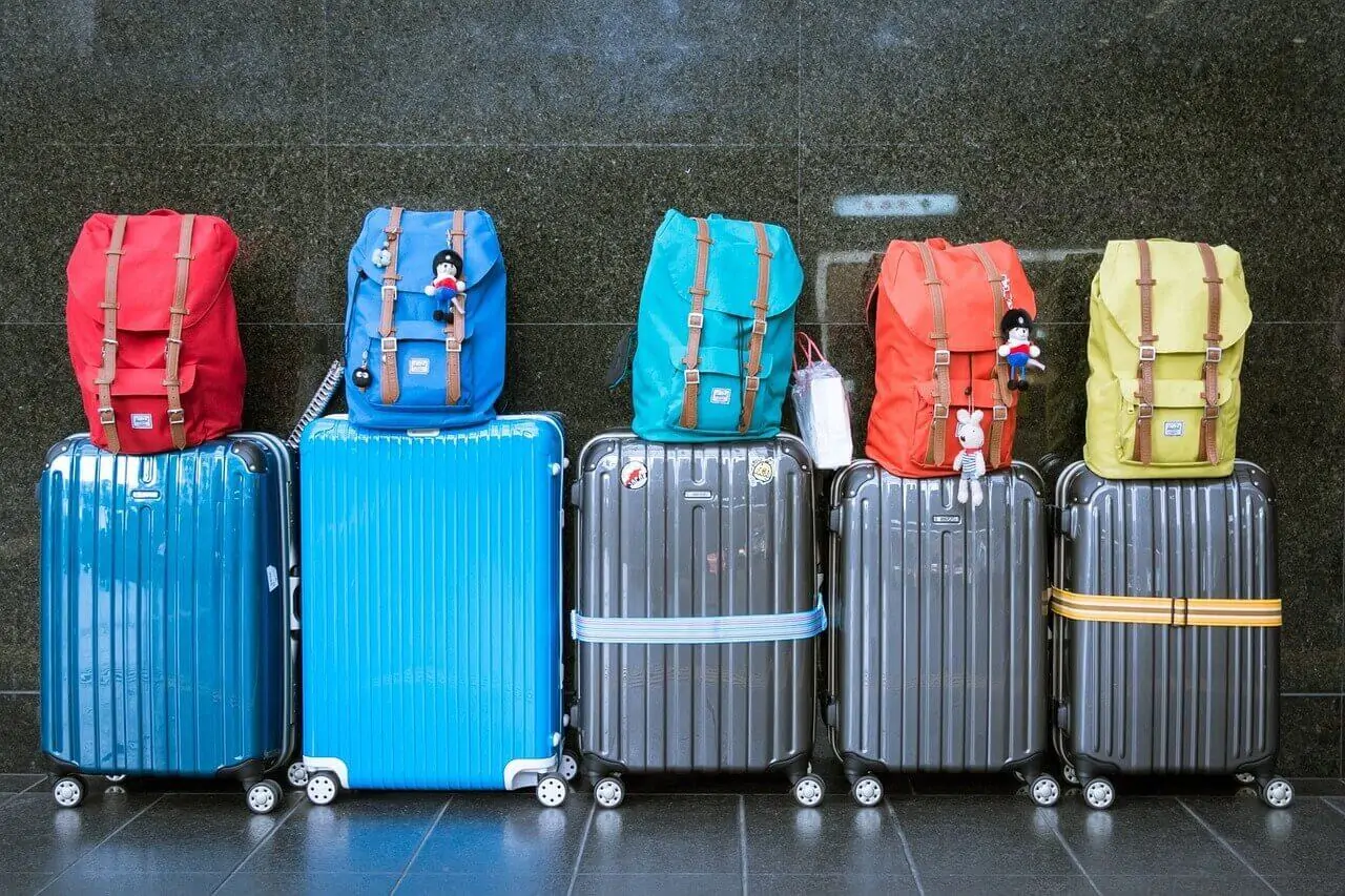 Bagagens lado a lado com mochilas coloridas empilhadas.