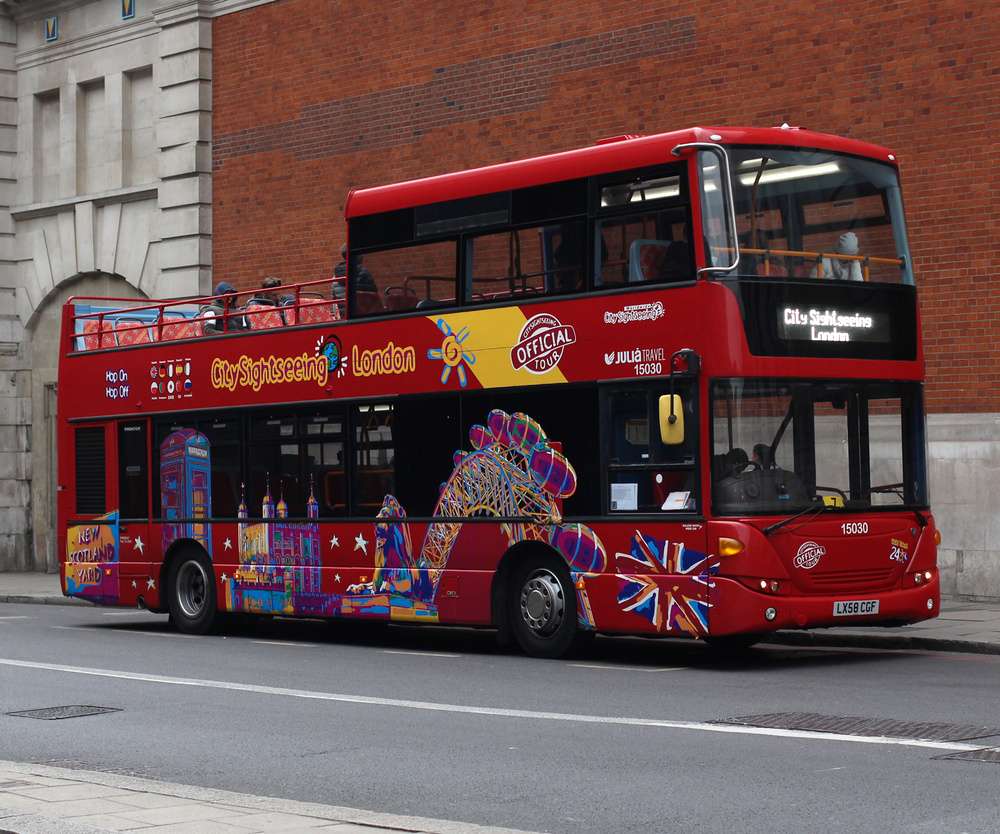 Ônibus turístico vermelho da empresa Sightseeing, visto durante o dia.