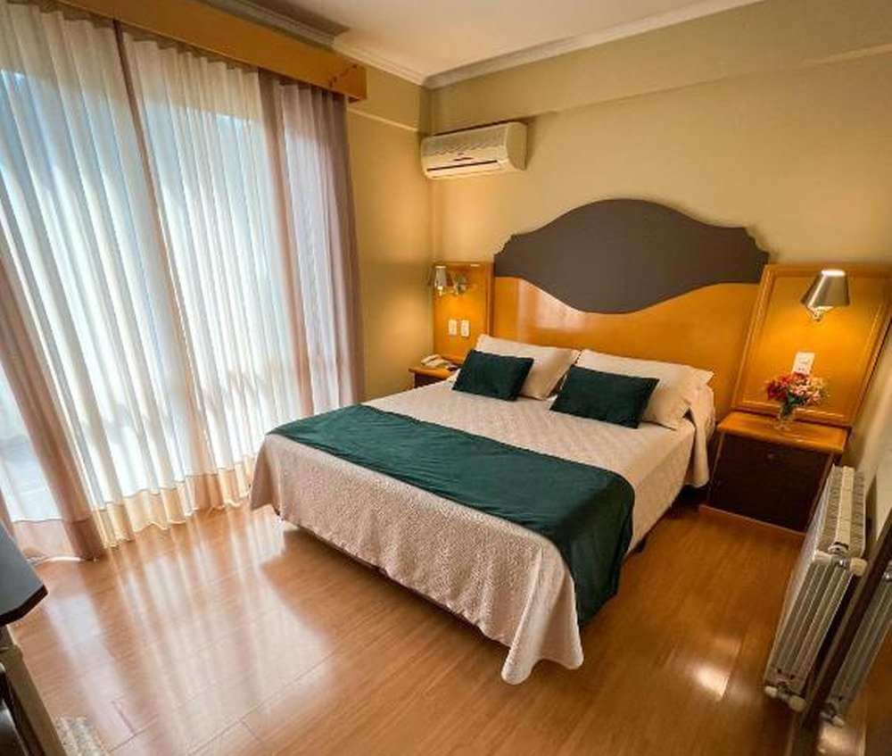Quarto do Hotel Vovó Carolina, com cama de casal e janelão.