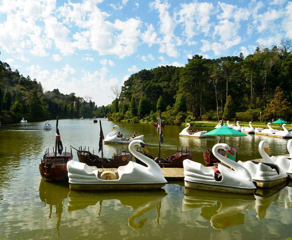 O Parque Lago Negro em Gramado, com as águas calmas do lago refletindo as árvores ao redor. Pedalinhos em formato de cisne estão disponíveis para passeio.