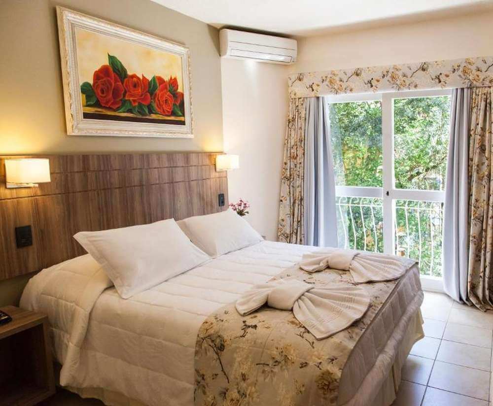 Quarto da Pousada Águia Branca, com cama de casal e decoração delicada.