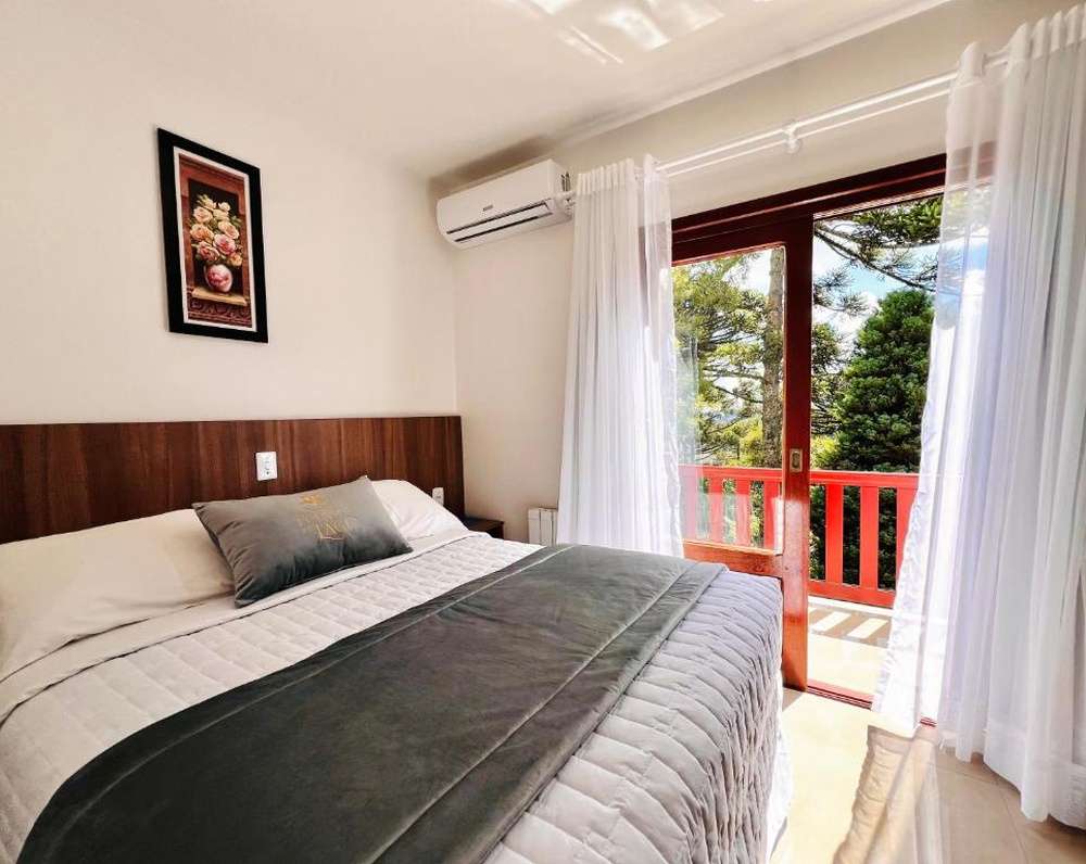 Quarto da Pousada do Lago, com cama de casal e varanda com vista para as árvores.