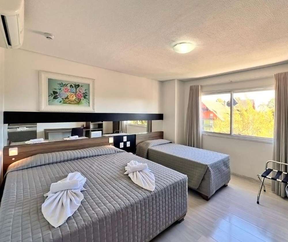 Quarto moderno do Sky Premium Hotel, com duas camas, decoração minimalista e uma janela grande com vista.