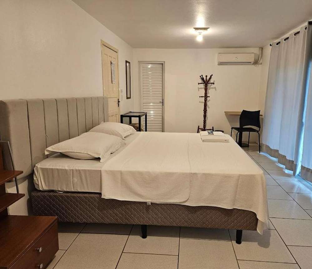 Quarto minimalista do Hostel & Suítes Stettin, com cama de casal e decoração moderna.