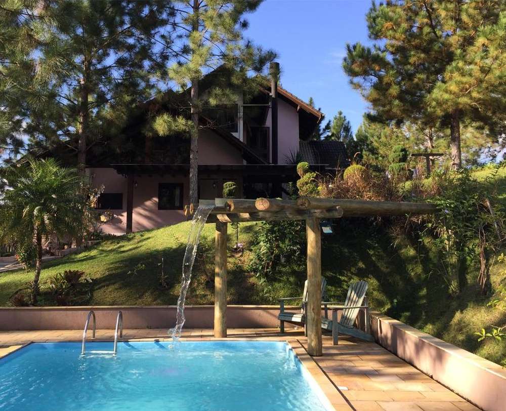 O exterior da Pousada Casarão Gastehaus, em uma área verde com casas simpáticas e piscina.