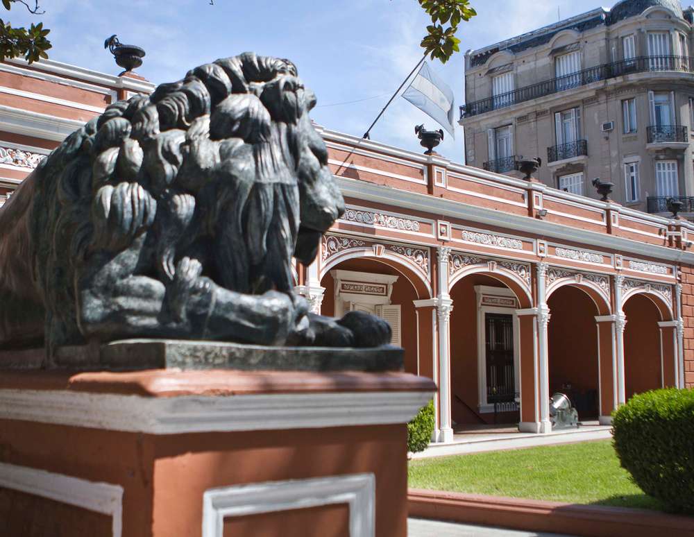 Uma estátua de um leão deitado sobre uma coluna, no jardim do Museu Histórico Nacional da Argentina.