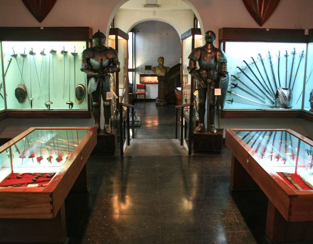 Exposição de armaduras e armas medievais no Museo de Armas de la Nación, em Buenos Aires, com vitrines que exibem espadas e outras armas históricas.