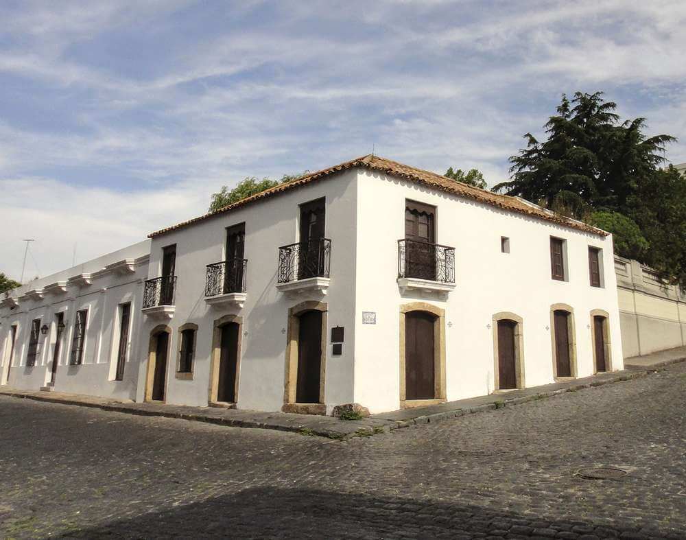 Fachada do Museu Espanhol em Colonia del Sacramento, Uruguai, com arquitetura colonial e paredes brancas.
